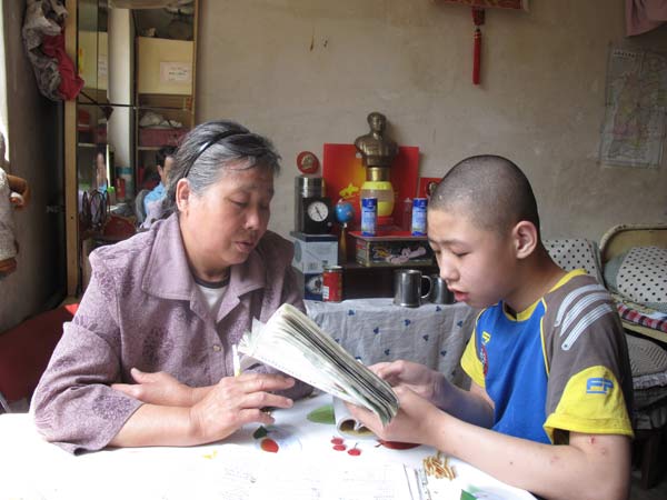 Chen Pei'e, 63, helps her epileptic grandson Chen Zhengshan study at home in Taiyuan, Shanxi province, on May 11. [ Photo / China Daily ]