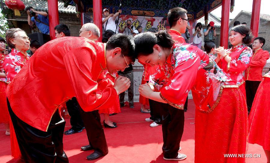 Brides and grooms bow to greet each other at a traditional Chinese wedding in Zhoucun Village of Zibo, east China's Shandong Province, May 27, 2012. Twenty pairs of couples from Beijing, Zhejiang, Fujian and Shandong took part in the traditional wedding on Sunday.
