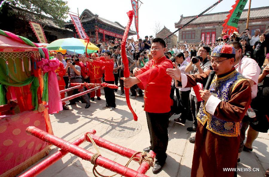 Bridegrooms pull bow at a traditional Chinese wedding in Zhoucun Village of Zibo, east China's Shandong Province, May 27, 2012. Twenty pairs of couples from Beijing, Zhejiang, Fujian and Shandong took part in the traditional wedding on Sunday.