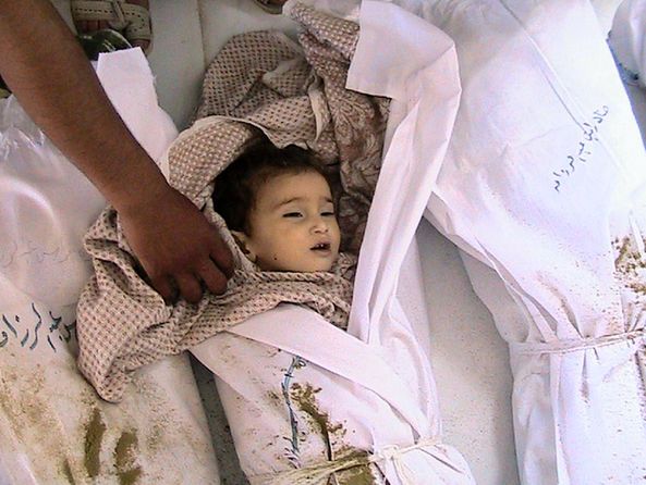 A handout picture released by the Syrian opposition's Shaam News Network shows the body of a Syrian child lying next to other shrouded bodies at the mortuary of a hospital in the Syrian town of Houla on May 26, 2012. [Xinhua]