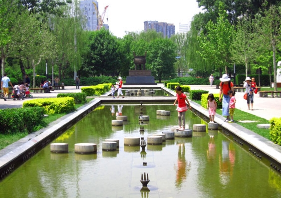 Children cross the fountain in Chaoyang Park's Art Square.