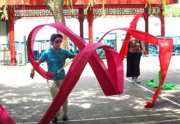 A woman enjoys twirling her ribbon in Beihai Park.