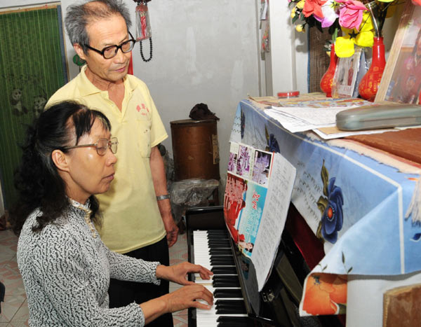 With her husband at her side, Xie Guizhi plays the piano at their home in Henan province. To fulfill his wife's wish, Wu Zheng collected recyclable waste for 20 years and eventually bought her a piano. [ Photo / for China Daily ]