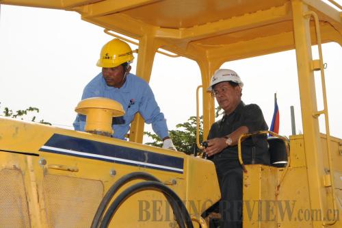 Cambodian Prime Minister Hun Sen (right) drives a bulldozer at the groundbreaking ceremony of a road expansion project funded with a soft loan from China on the outskirts of Phnom Penh on February 14 [Lei Baisong]