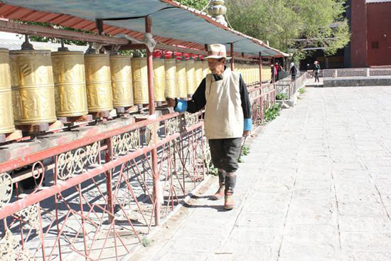 A believer is turning prayer wheels. [Photo/ China Tibet Online]