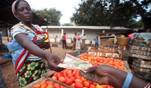 A woman purchases vegetables at a local market. [FAO]