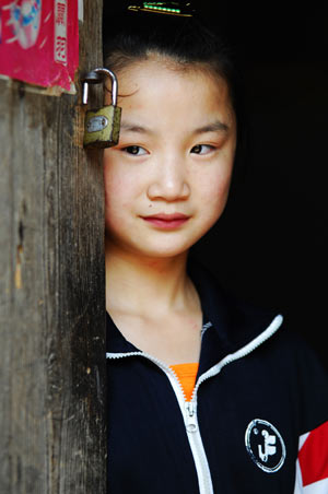 Zhou Jing, one of the 'left-behind children', stands at the door of her home in Fushan township, Henan province. [ Photo / China Daily ]