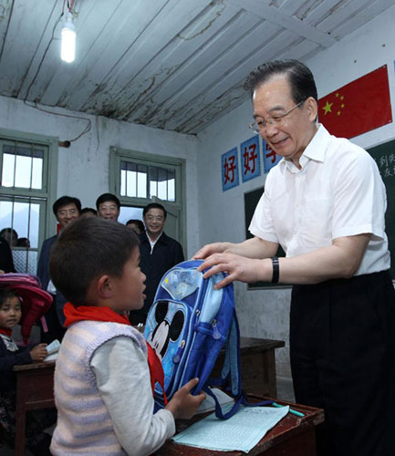 Chinese Premier Wen Jiabao gives a school bag to a child in the Maoping Primary School in Maoping Village, Morong Town of Guzhang County, central China's Hunan Province, May 25, 2012.[ Photo / Xinhua ]