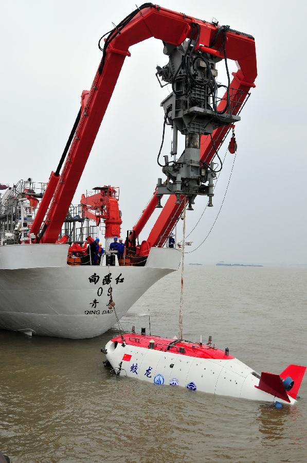 Workers move China's manned submersible Jiaolong into water in Jiangyin, east China's Jiangsu Province, June 1, 2012. The Jiaolong on Friday held two diving practices for its challenge of a 7,000-meter dive to the Mariana Trench slated for June 3.