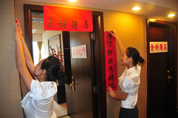 Workers put up a couplet with blessing words for success in the college entrance examination at a hotel in Nanchong, Sichuan province, on May 28. [ Photo / China Daily ]