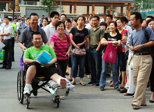 Parents of Chai Zixin push their son's wheelchair into the national college entrance examination site at Yucai Middle School in Xi'an, capital of Northwest China's Shaanxi province, on Thursday. Chai broke his leg about 10 days before the exam. [ Photo / China Daily ]