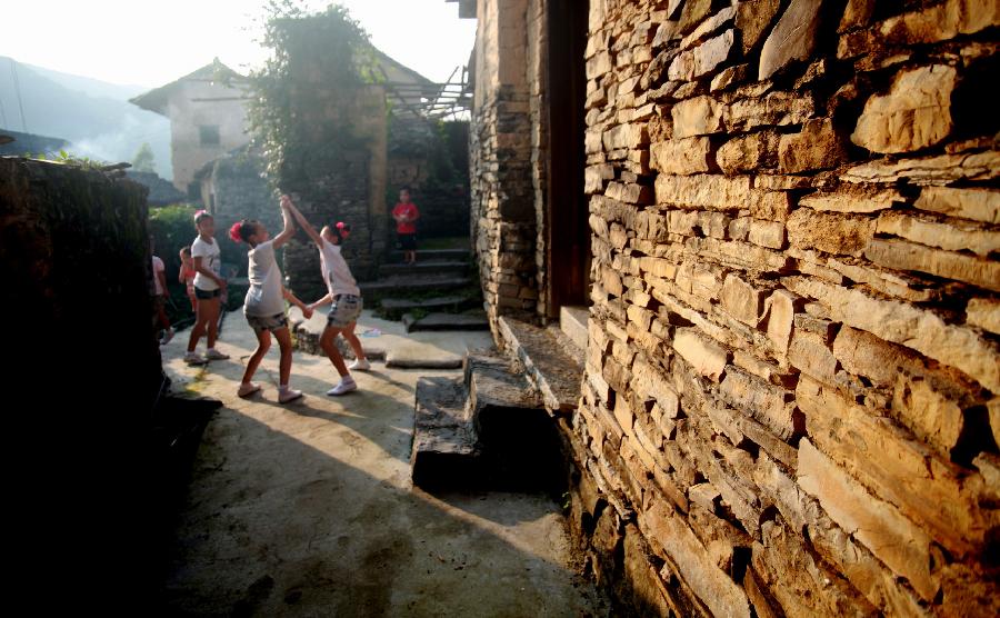 Children play in Donghuang Village of Rong'an County, south China's Guangxi Zhuang Autonomous Region, June 9, 2012. Stone houses, stone walls, stone steps and stone bridges are still well-preserved here after a history of more than 350 years. Residents in this stone village lead a different life now as local economy develops. However, most of them perfer to living in traditional stone houses, which are warm in winter and cool in summer. (Xinhua/Wang Zichuang) 