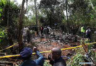 Rescue workers investigate the helicopter crash site in Ngong Forest in the outskirts of Nairobi, Kenya, June 10, 2012. Six Kenyan government officials, including Internal Security minister Professor George Saitoti and his deputy Orwa Ojode, were killed when a police helicopter crashed early Sunday near Nairobi.