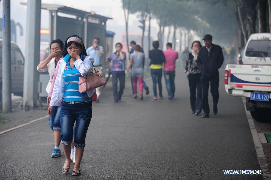 People pass by the spot of accident in Wangjiao chemical plant in Shenyang, capital of northeast China's Liaoning Province, June 12, 2012. A depot of the factory exploded at 4:30 p.m. in the Yuhong district, shattering windows at a distance of 200 meters and resulting in a massive cloud of smoke, witnesses said.