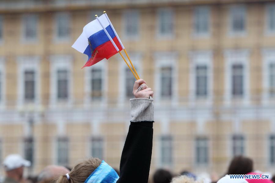 A person holds Russian flags at the Place Square in front of the Winter Palace while taking part in the celebration of the &apos;Day of Russia&apos; in St. Petersburg, Russia, June 12, 2012. Russia celebrated on Tuesday its national holiday, the &apos;Day of Russia&apos;, with mass culture events held throughout the country.