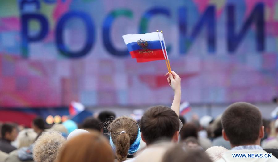 A person holds Russian flags at the Place Square in front of the Winter Palace while taking part in the celebration of the 'Day of Russia' in St. Petersburg, Russia, June 12, 2012. Russia celebrated on Tuesday its national holiday, the 'Day of Russia', with mass culture events held throughout the country. 