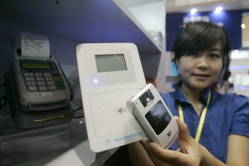 A woman holds up an intelligent handset (foreground) and a receiver device during a financial expo in Beijing in 2009. The handset combines the payment and SIM card together, which can be used to book tickets, shop online and make payments.