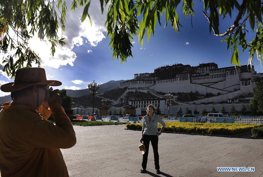 Two foreign tourists take photos at potala palace square in Lhasa, southwest China's Tibet Autonomous Region, June 12, 2012. As the weather turns warm, Tibet faced a tourism peak recently. (Xinhua/Wen Tao)