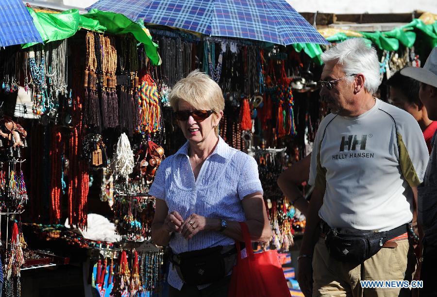 Foreign tourists visit Porgor Street in Lhasa, southwest China's Tibet Autonomous Region, June 12, 2012. As the weather turns warm, Tibet faced a tourism peak recently. (Xinhua/Wen Tao)