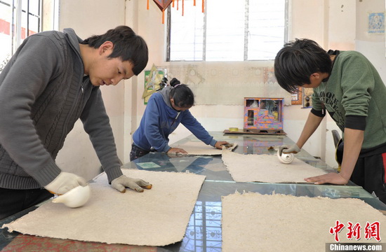 Workers are polishing the paper with sea snails. (CNS Photo / Li Lin)