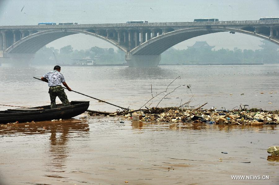 A sanitation worker clear the garbage brought by flood on the Changsha reach of Xiangjiang River in Changsha, central China's Hunan Province, June 13, 2012. Xiangjiang River's flood peak passed its Changsha reach smoothly on Wednesday. (Xinhua/Long Hongtao) 