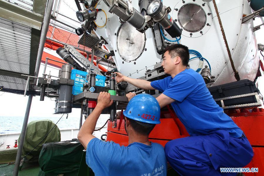 Staff members adjust devices on the deep-sea submersible, Jiaolong, aboard Xiangyanghong 09, the submersible's oceanographic mother ship, June 14, 2012. 