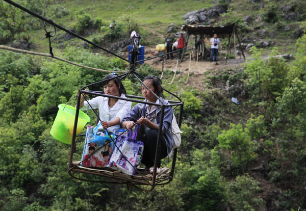 Two villagers cross a gorge on a liusuo, a cable-car-style mechanism between two cliffs, in Shuicheng county, Guizhou province in April.[ Photo / China Daily ]
