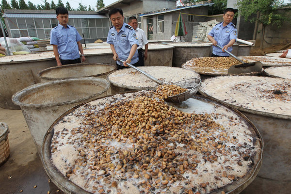 Police officers examine decayed beans at an illegal food processing plant in Cangshan county, East China's Shandong province, on June 1. The plant has been shut down. Initial investigation found its products, fried beans and peanuts, were mainly sold to rural market. [Zhu Wutao / For China Daily]     