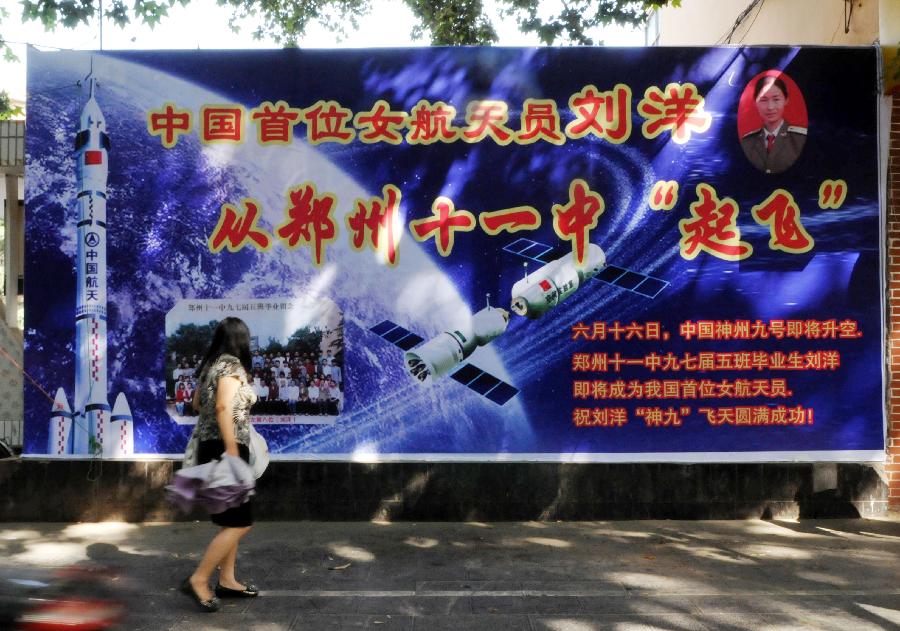 A citizen walks past a poster showing the image of Liu Yang, one of the three taikonauts who will be carried by the Shenzhou-9 spaceship for China's first manned space docking mission with the orbiting Tiangong-1 space lab module, in the No.11 middle school where Liu graduated in Zhengzhou, capital of central China's Henan Province, June 12, 2012. Zhengzhou is the hometown of Liu Yang. (Xinhua/Li Bo) 