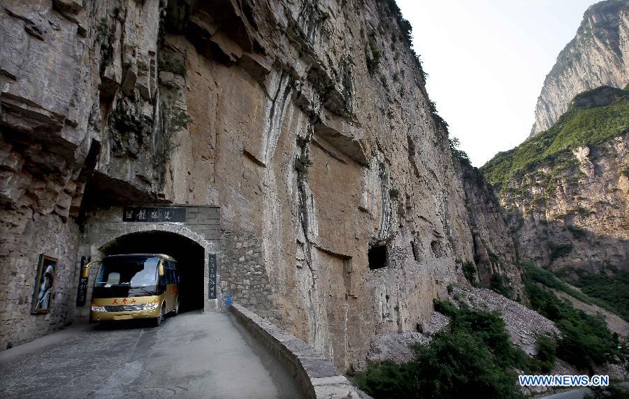 A shuttle bus moves on a way towards a scenic area at Huilong Village in the Taihang Moutains in Huixian County, central China&apos;s Henan Province, June 14, 2012