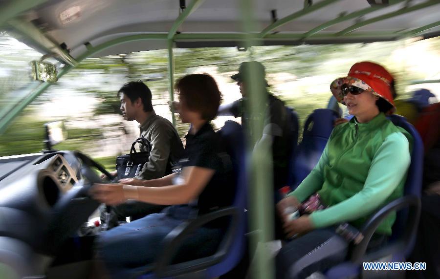 Tourists take an electric vehicle to a scenic area at Huilong Village in the Taihang Moutains in Huixian County, central China&apos;s Henan Province, June 14, 2012.