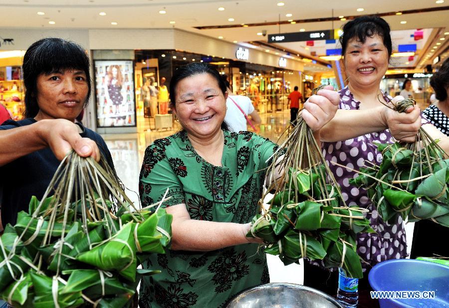 Contestants show their self-made Zongzi, a pyramid-shaped dumpling made of glutinous rice wrapped in bamboo or reed leaves, during a Zongzi making contest in Fuzhou, capital of southeast China's Fujian Province, June 22, 2012, to greet the upcoming Chinese Dragon Boat Festival, which falls on June 23 this year. [Xinhua]