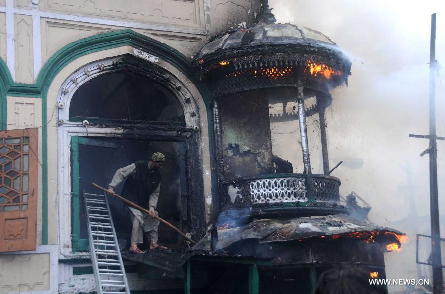 A local resident tries to douse the flames of shrine window in Srinagar, summer capital of Indian-controlled Kashmir, June 25, 2012. A 200-year-old Muslim Sufi shrine gutted in a fire incident Monday in Indian-controlled Kashmir, police said. The historical shrine of Sheikh Syed Abdul Qadir Jeelani ( locally called Dastgeer Sahib) is in old part of Srinagar city. (Xinhua/Javed Dar) 