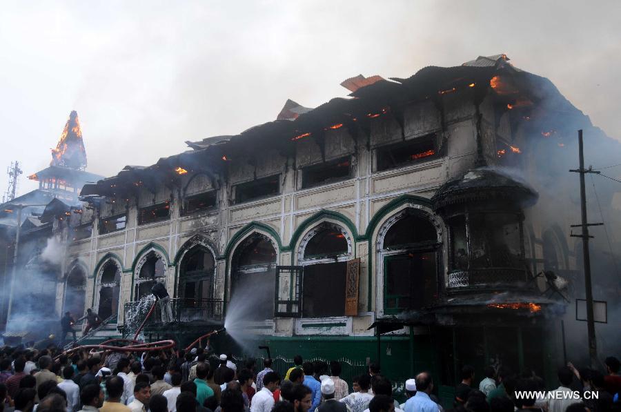 Smoke rises from the gutted shrine of Sheikh Syed Abdul Qadir Jeelani as people crowd the streets in Srinagar, summer capital of Indian-controlled Kashmir, June 25, 2012. A 200-year-old Muslim Sufi shrine gutted in a fire incident Monday in Indian-controlled Kashmir, police said. The historical shrine of Sheikh Syed Abdul Qadir Jeelani ( locally called Dastgeer Sahib) is in old part of Srinagar city. 