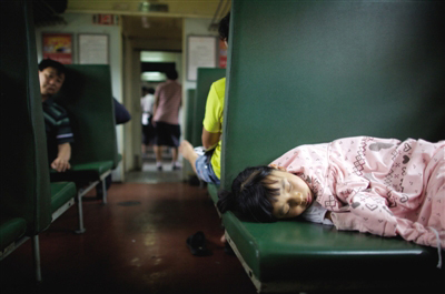 This photo, taken on June 25, 2012, shows a child sleeping the green train. [Photo / The Beijing News]