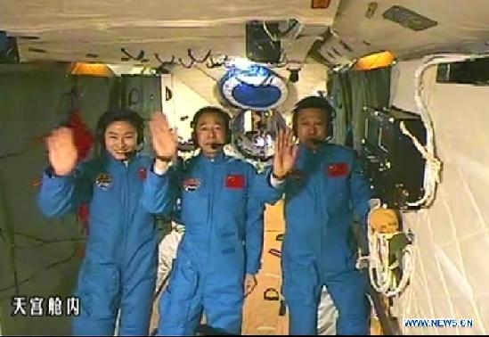 This screen shot taken on June 26, 2012 shows the Chinese astronauts who are conducting scientific tests in Tiangong 1 space lab module waving hands. Chinese President Hu Jintao came to the Beijing Aerospace Control Center on Tuesday and talked with the astronauts. [Xinhua] 