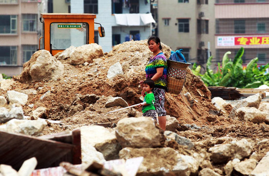 A woman surnamed Wang walks on the construction site with her 2-year-old granddaughter in Hengqin Island, Zhuhai city, Guangzhou province on June 15, 2012. [Photo/CFP]