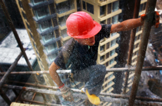 A worker stands on scaffolding for aerial work on a construction site in Hengqin Island, Zhuhai city, Guangzhou province on June 15, 2012. [Photo/CFP] 