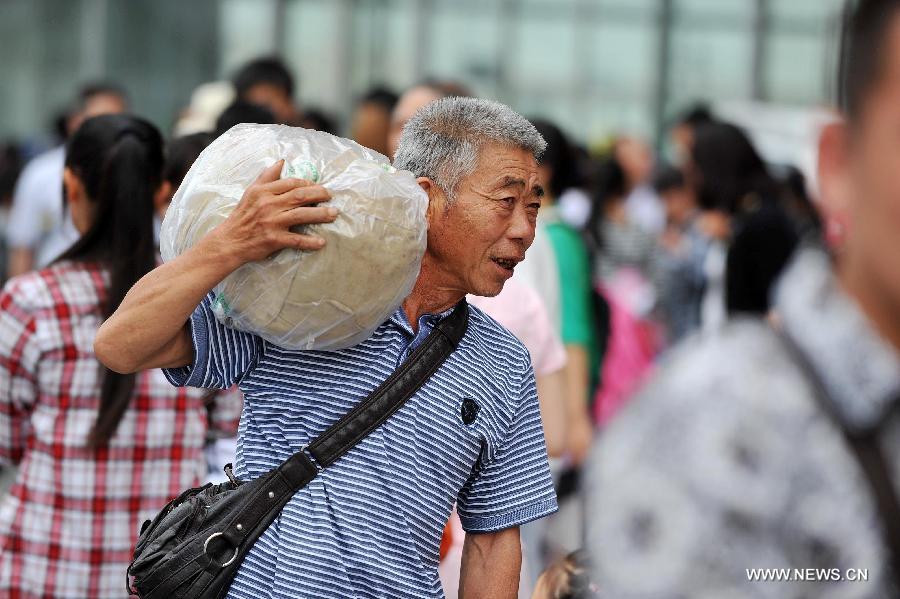 A passenger carries his luggage at Yinchuan Railway Station in Yinchuan, capital of northwest China's Ningxia Hui Autonomous Region, July 3, 2012