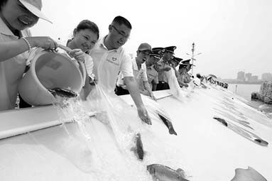 People from Guangdong province, Hong Kong and Macao release fish into the Dongjiang River in Huizhou, Guangdong province, in June 2011.[China News Service] 