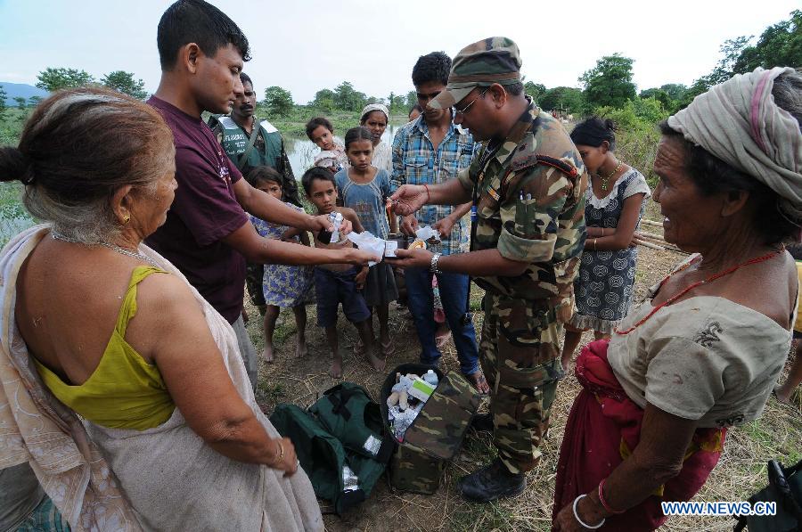 Villagers receive medicine from an Indian army doctor in Fateki village in the worst flood affected Sonitpur district of northeastern state Assam, India, on July 3, 2012. At least 81 people have died and 2.2 million were forced to leave their homes over the last week as torrential monsoon rains trigger floods across India's northeast, officials said. (Xinhua) 