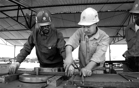 Chinese workers train their Angolan colleagues to roll steel at a CITIC Construction Co Ltd worksite in Luanda, the capital city of Angola.