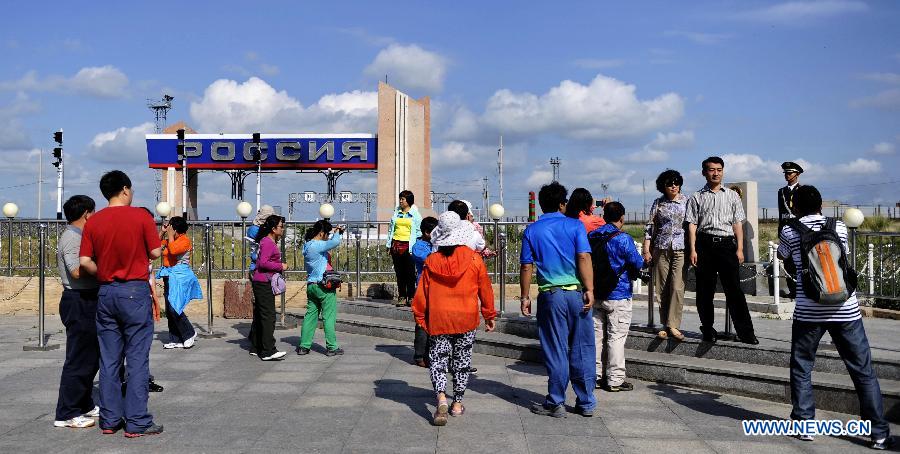 Tourists visit a locomotive at the scenic resort of Sino-Russian border gate in Manzhouli, north China's Inner Mongolia Autonomous Region, July 3, 2012