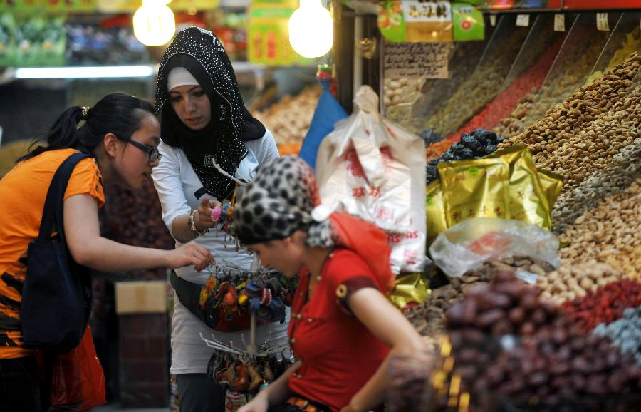 Tourists buy local souvenirs in Xinjiang International Grand Bazaar in Urumqi, northwest China's Xinjiang Uygur Autonomous Region, July 2, 2012. As travel season is coming, Xinjiang International Grand Bazaar attracts quite a lot tourists. (Xinhua/Zhao Ge) 