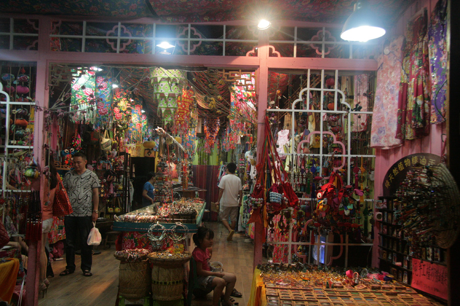 A shop sells various handicrafts in a commercial street of Fenghuang (phoenix) ancient town on June 28. [CnDG by Jiao Meng]