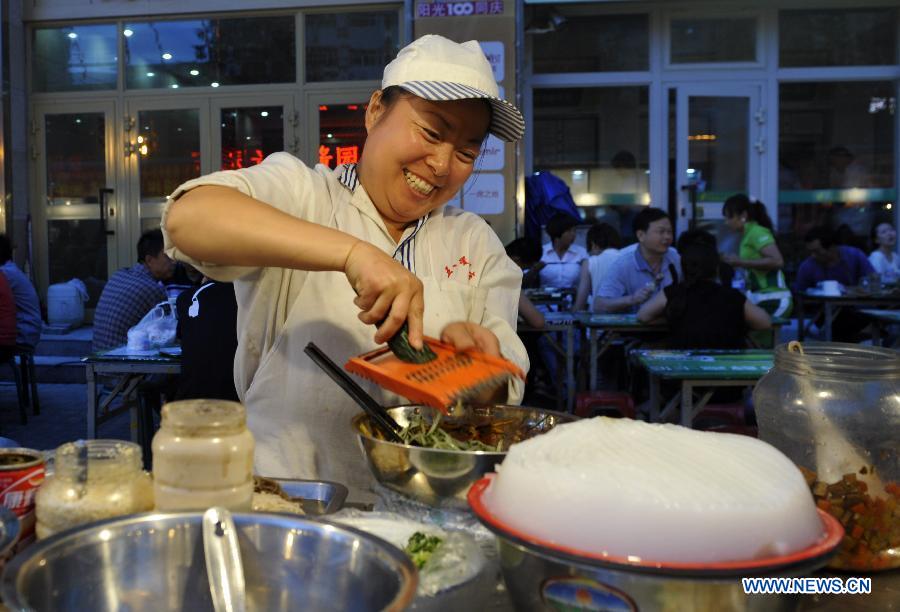 A chef cooks snacks at an evening market in Urumqi, capital of northwest China's Xinjiang Uygur Autonomous Region, July 2, 2012.