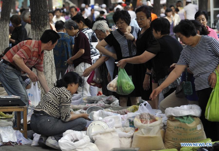 Citizens buy goods at a market in Urumqi, capital of northwest China's Xinjiang Uygur Autonomous Region, July 2, 2012.