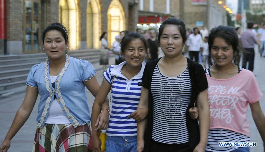 People take a walk at the Xinjiang International Grand Bazaar in Urumqi, capital of northwest China's Xinjiang Uygur Autonomous Region, July 2, 2012