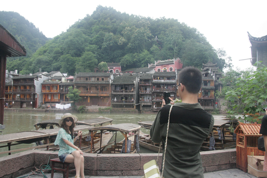 A female visitor takes a photo in Fenghuang (Phoenix) ancient town on June 28. This small town receives over 3 million visitors each year. [CnDG by Jiao Meng]