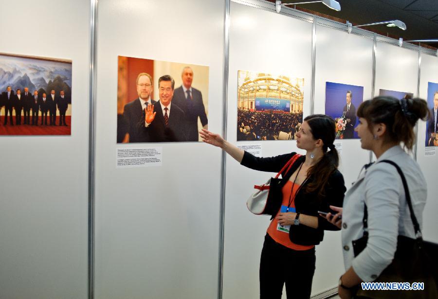 Visitors look at photos on display during a photo exhibition of the first World Media Summit in Beijing, presented by Xinhua News Agency, in Russian capital Moscow on July 5, 2012. 